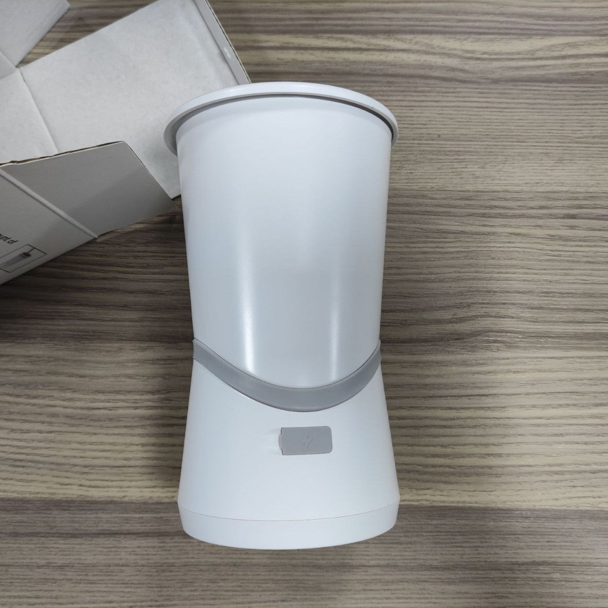 White cylindrical device with a gray band on a wooden surface